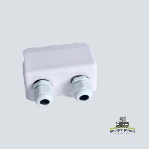 קופסת חיבורים פוטו-וולטאית לבנה מפלסטיק עם שתי בלוטות כבלים בצד אחד, מיועדת להתקנות אנרגיה סולארית מאובטחות על הגג וניהול יעיל של כבלי חשמל במערכות אנרגיה מתחדשת; רכיב אידיאלי עבור פאנלים סולאריים פוטו-וולטאיים, תשתית לייצור חשמל ואחסון אנרגיה (אגירה סולרית), מוצגת על רקע בהיר חלק.